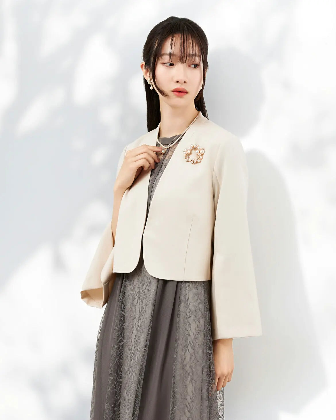 袖口のスリットデザインが手元を華やかに見せるアイボリーのノーカラー